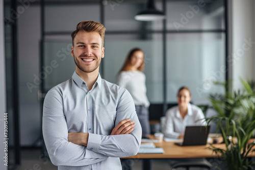 A portrait of a cheerful businessman standing in a conference room with his arms crossed.