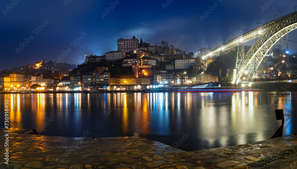 Panoramic long exposure night view of Porto, Portugal, the Douro River, and Dom Luis Bridge during a rainy night