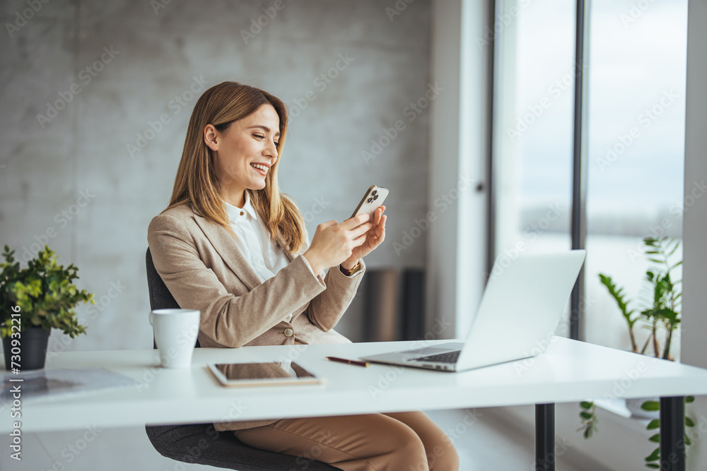 Mature businesswoman talking with somebody while sitting at office desk and working on laptop. Happy business woman chatting on digital gadgets online, holding mobile phone Mature businesswoman talking with somebody while sitting at office desk and working on laptop. Happy business woman chatting on digital gadgets online, holding mobile phone