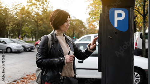 Fotografía Woman Pays For Car Parking Via Parking Meter Using Credit Card