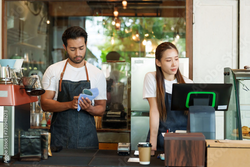  cafe owner, multiracial male business couple, cleaning coffee cups coffee maker. Asian girlfriend checking orders store closed. credit card swipe machine paper coffee cups. cafe small business.