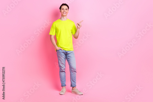 Full length photo of cheerful good mood man dressed yellow t-shirt showing finger empty space isolated pink color background