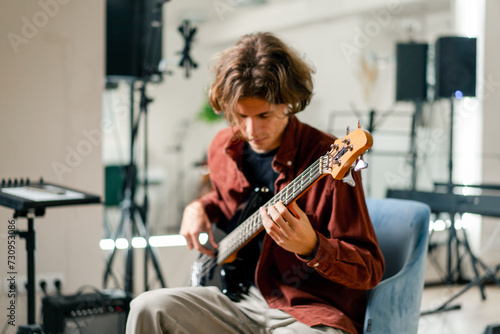 rock artist with long hair with electric guitar in recording studio playing own track musical instrument string melodies