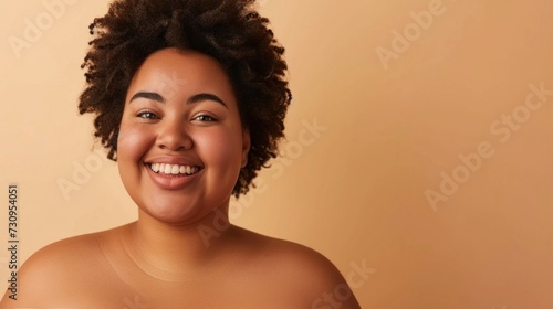 A joyful woman with curly hair and a radiant smile set against a warm neutral background.