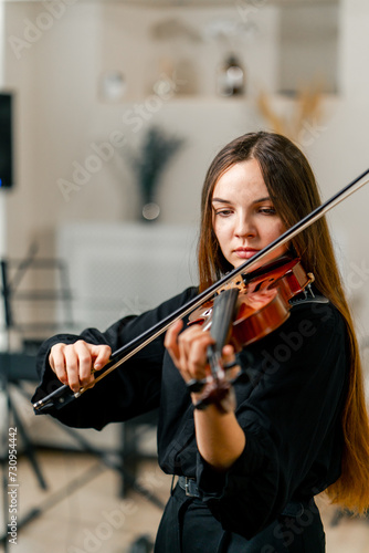 A girl violinist rehearses the melody of a classical piece of music on the violin in a music center at a rehearsal