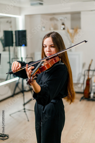 A girl violinist rehearses the melody of a classical piece of music on the violin in a music center at a rehearsal