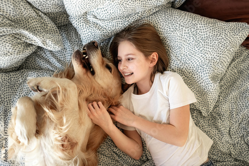 Cute Little Girl Playing With Golden Retriever Dog In Bed