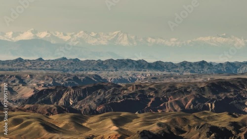 Mountainous terrain with beautiful skin rocky slopes with snow peaks background. Martian plateau landscape in Kazakhstan at summer sunny sunset.
