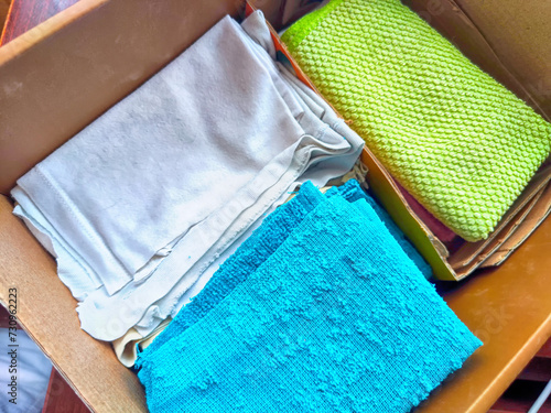 Old rags and eco-friendly cleaning cloths neatly arranged in a cardboard box. Old rags and things for cleaning and cleanliness in house. Eco-friendly use of recyclables