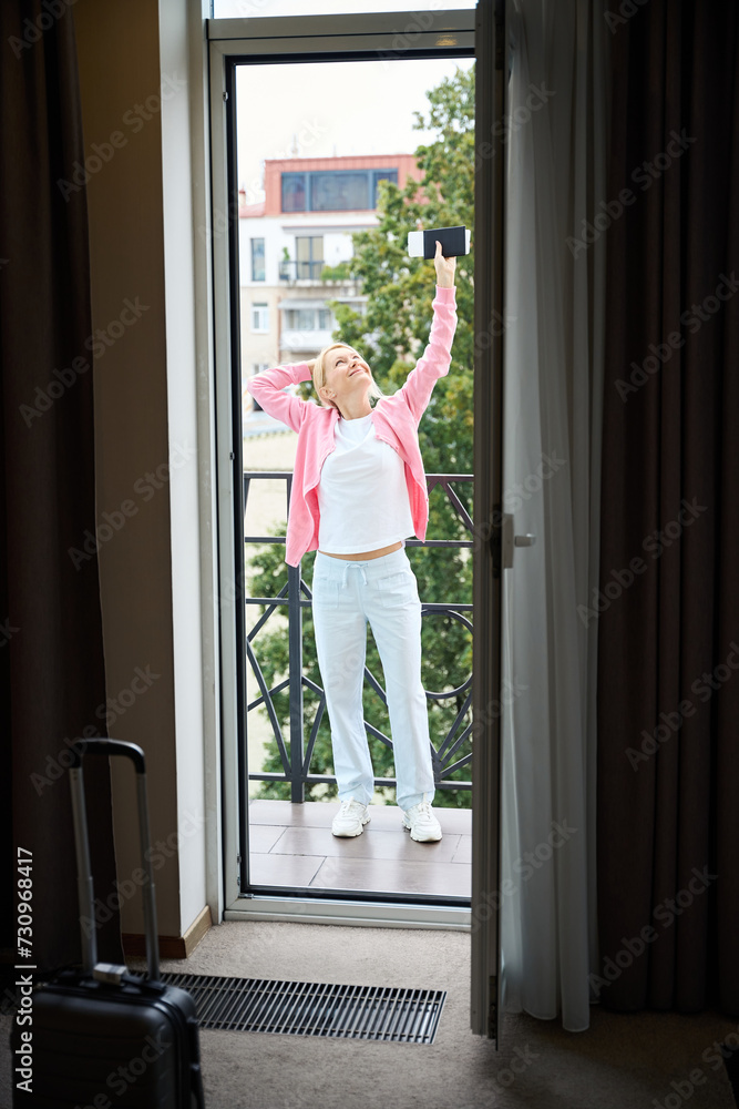 Smiling female tourist rejoicing at her arrival at luxury suite Smiling female tourist rejoicing at her arrival at luxury suite