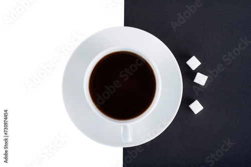 A cup of black coffee with cubes of sugar on a black and white background isolated