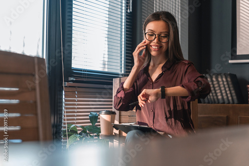 Obraz na plátně Portrait of businesswoman professional talking on cellphone and looking on watch