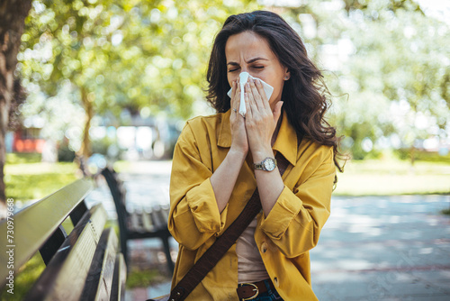 Woman has sneezing. Young woman is having flu and she is sneezing. Sickness, seasonal virus problem concept. Woman being sick having flu sneezing. photo
