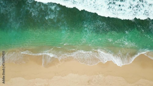 Aerial view of an empty sandy beach with slow moving beautiful waves on a sunny day. photo