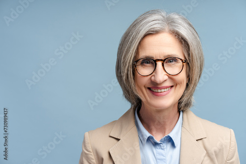 Smiling confident business woman, lawyer, financier wearing stylish glasses looking at camera isolated on blue background. Portrait of confident gray haired politician. Successful business, career 