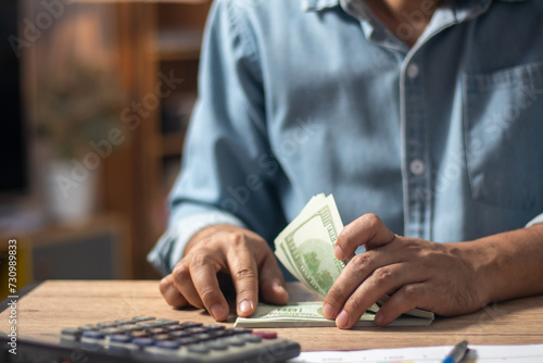 A man meticulously counts dollar bills, reflecting the concept of currency management in investments, salaries, shopping, and business transactions.