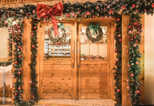 Wooden door decorated with christmas tree, ball, ribbon at front of cafe