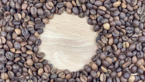 Space for your logo or text against a backdrop of rotating freshly roasted coffee beans on a wooden background. Copy space, flat layout.