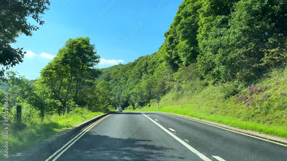 Car windscreen view driving on A57, Snake Pass road through woodland on a beautiful sunny day, roadside warning signs. Car windscreen view driving on A57, Snake Pass road through woodland on a beautiful sunny day, roadside warning signs.