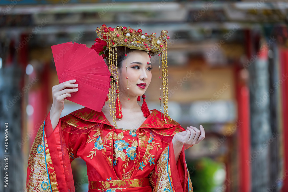 portrait of a woman. person in traditional costume. woman in traditional costume. Beautiful young woman in a bright red dress and a crown of Chinese Queen posing against the ancient door. 