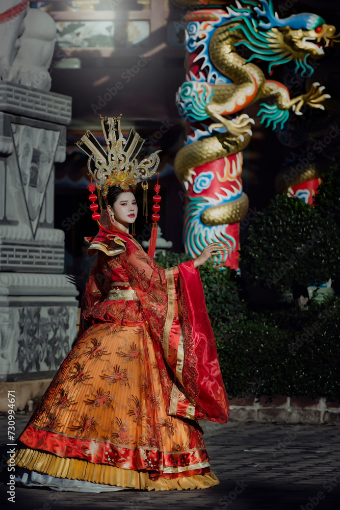 portrait of a woman. person in traditional costume. woman in traditional costume. Beautiful young woman in a bright red dress and a crown of Chinese Queen posing against the ancient door. 