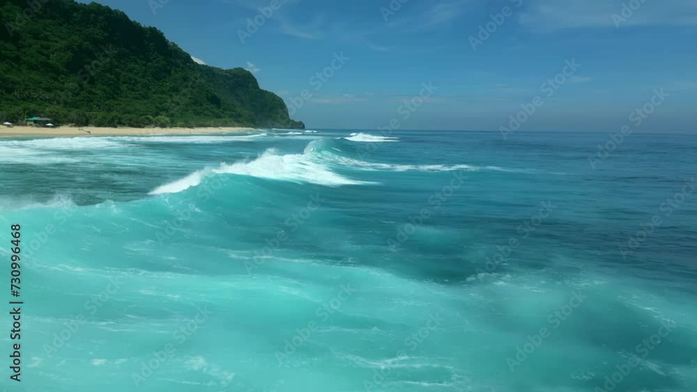 Aerial low flying over the waves of the ocean on a sunny day. Aerial low flying over the waves of the ocean on a sunny day.