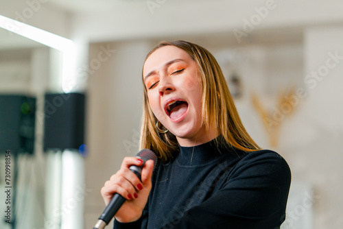 a beautiful young girl sings in a vocal lesson with a microphone in her hands during a lesson at a music school