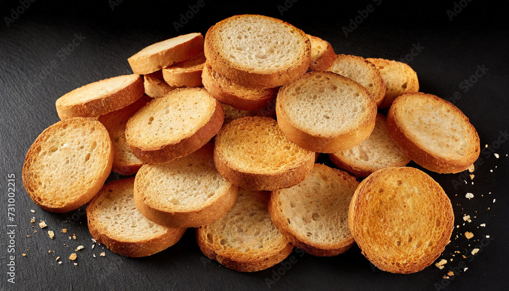 Round bread rusks pile falling, whole wheat toast slices isolated on black background, top view