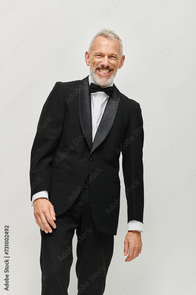 handsome cheerful mature man in black elegant tuxedo with bow tie smiling happily at camera handsome cheerful mature man in black elegant tuxedo with bow tie smiling happily at camera