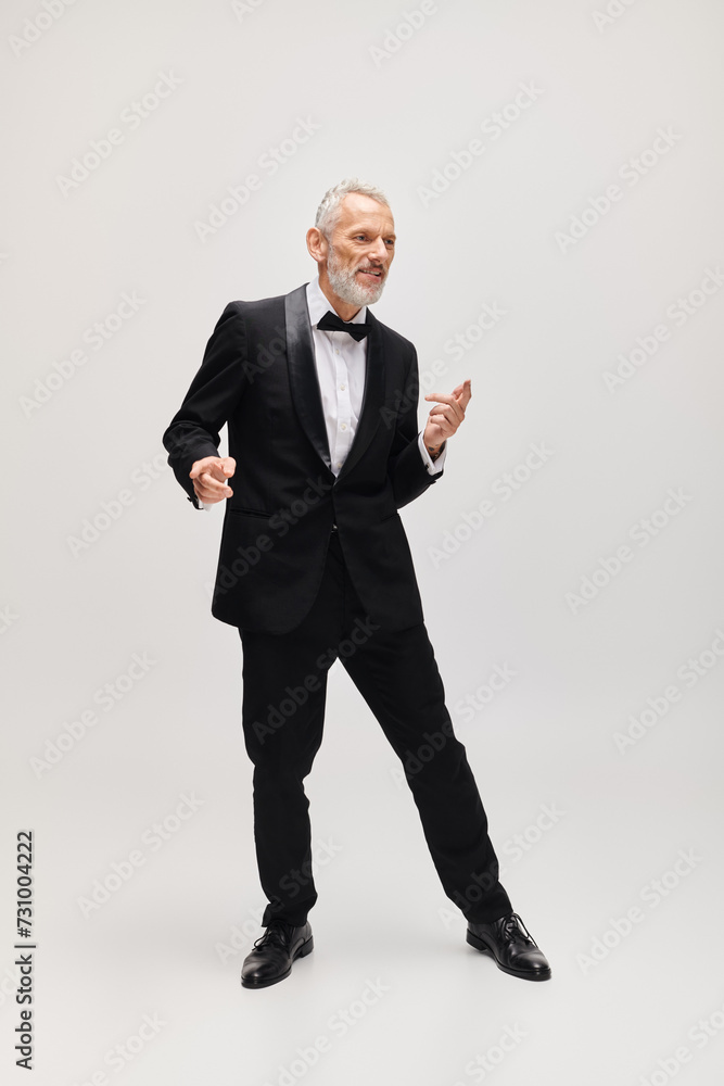 handsome cheerful mature man with gray beard and bow tie in elegant tuxedo dancing actively handsome cheerful mature man with gray beard and bow tie in elegant tuxedo dancing actively