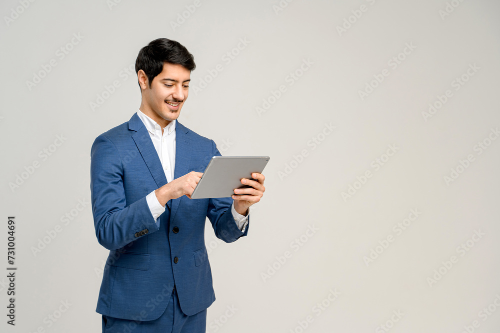 Young businessman in a business suit interacts with a digital tablet, his expression one of pleasant focus, perfect for illustrating the integration of modern technology in everyday professional tasks Young businessman in a business suit interacts with a digital tablet, his expression one of pleasant focus, perfect for illustrating the integration of modern technology in everyday professional tasks