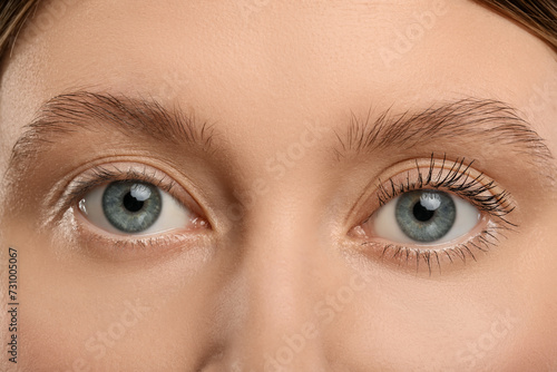 Woman showing difference in eyelashes length after mascara applying, closeup