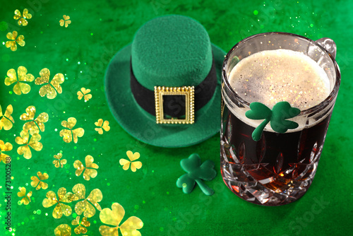 St. Patrick's day. Beer, decorative clover leaves and leprechaun hat on green table, space for text