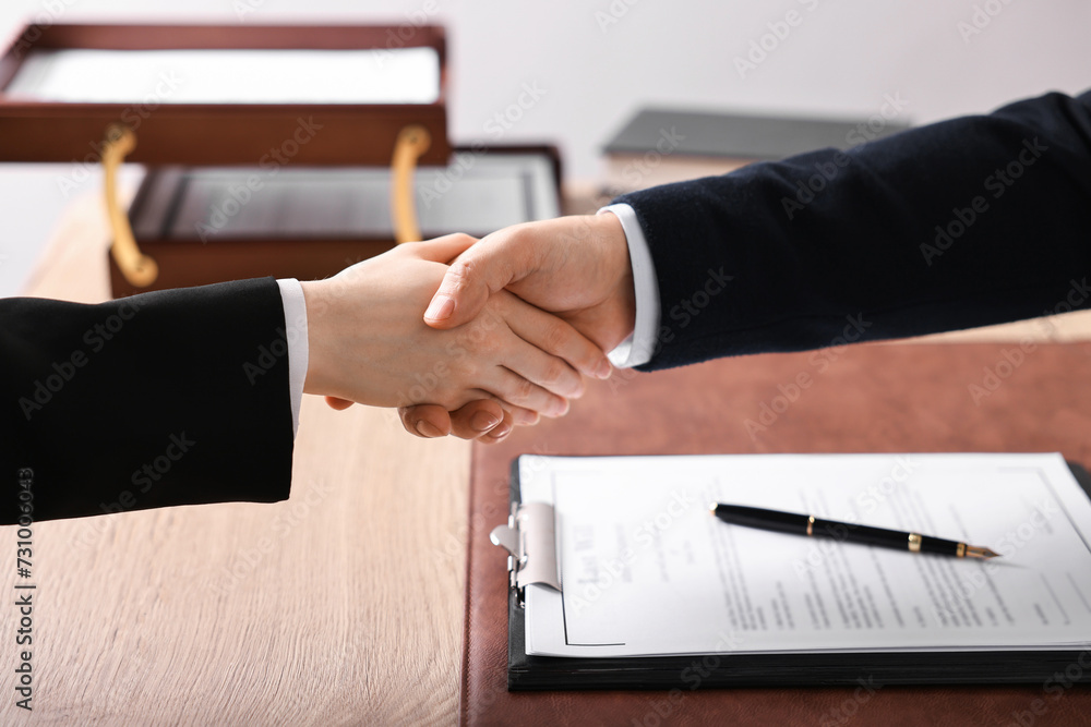 Notary shaking hands with client at wooden table in office, closeup Notary shaking hands with client at wooden table in office, closeup