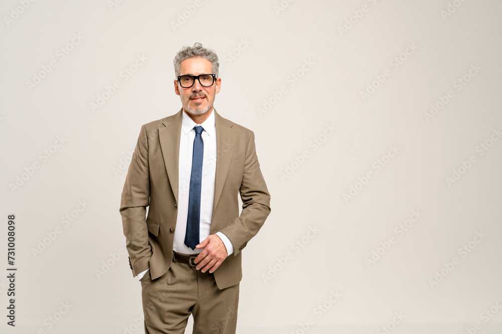 High-skilled senior businessman stands with one hand in his pocket, displaying a look of approachability and confidence against a light neutral background, perfect for corporate branding High-skilled senior businessman stands with one hand in his pocket, displaying a look of approachability and confidence against a light neutral background, perfect for corporate branding