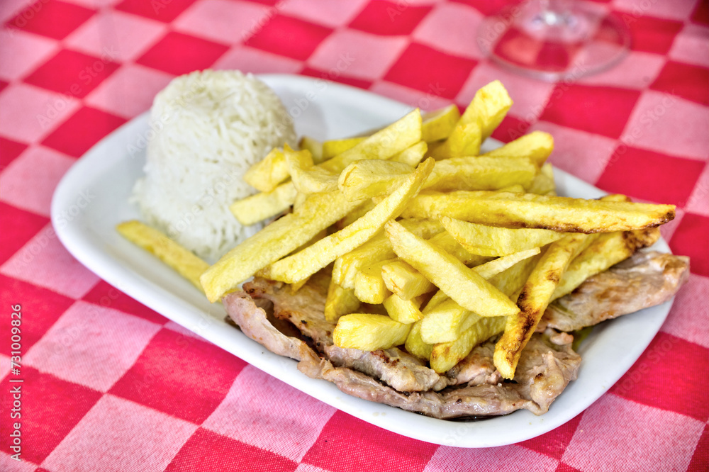 Grilled pork chops at a restaurant, served with rice and golden fries. A delectable dish capturing the essence of dining out in style. Grilled pork chops at a restaurant, served with rice and golden fries. A delectable dish capturing the essence of dining out in style.
