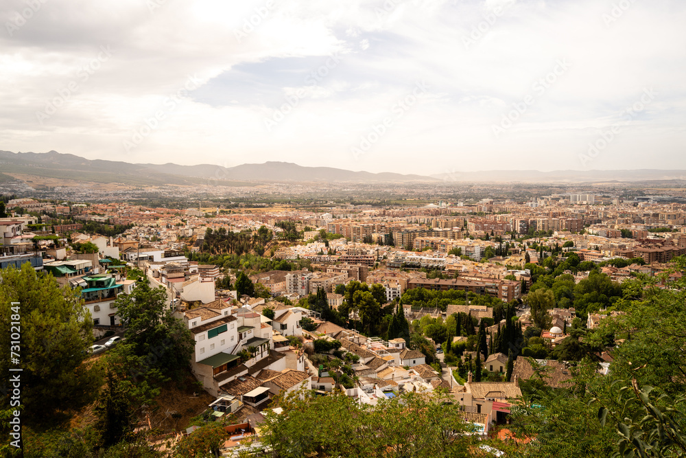 Granada, Spain, panoramic view of the city with mountains in background during hazy day. white buildings and trees, residential and commercial buildings. copy space no people, logos.