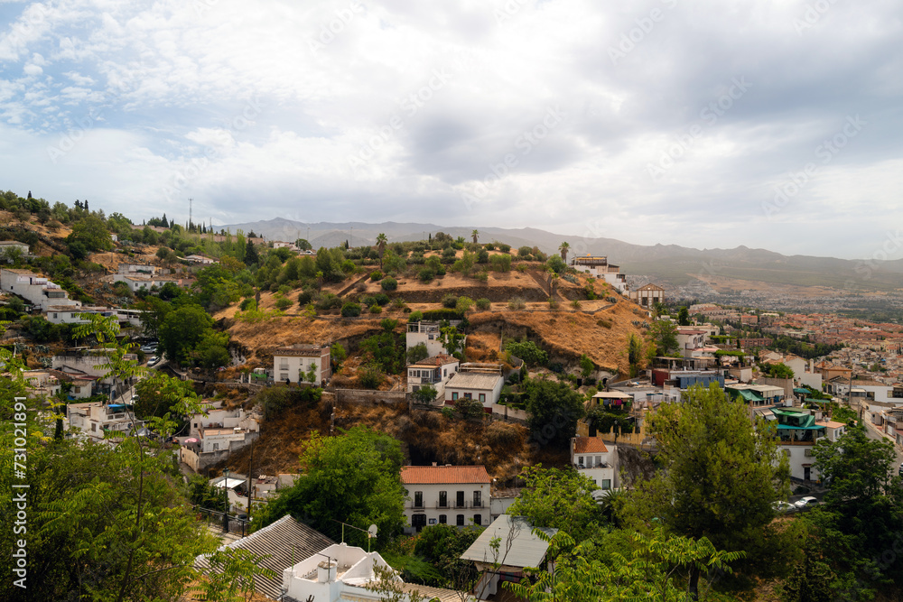 Granada, Spain, panoramic view of the city with mountains in background during hazy day. white buildings and trees, residential and commercial buildings. copy space no people, logos.