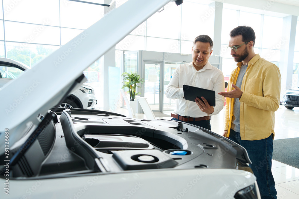 Manager consults a man in a car dealership Manager consults a man in a car dealership