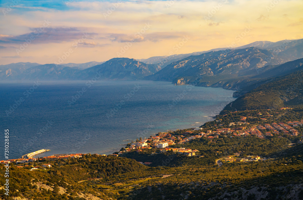 Coastal village of Cala Gonone in Sardinia during sunset, photographed from above with surrounding mountains and Tyrrhenian Sea. Coastal village of Cala Gonone in Sardinia during sunset, photographed from above with surrounding mountains and Tyrrhenian Sea.