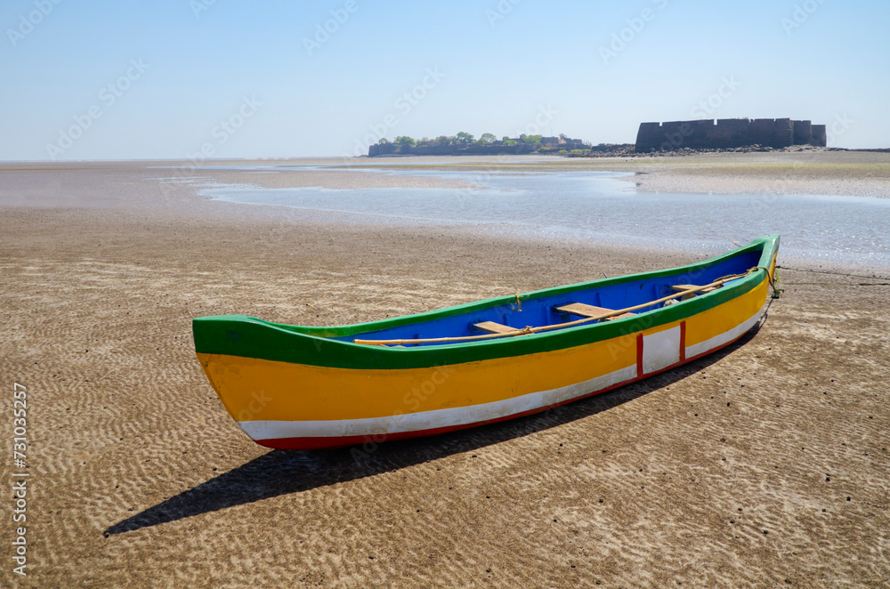 Colorful boat on the Alibaug beach and Alibaug Fort in the background, Alibaug, Maharashtra, India, Asia.