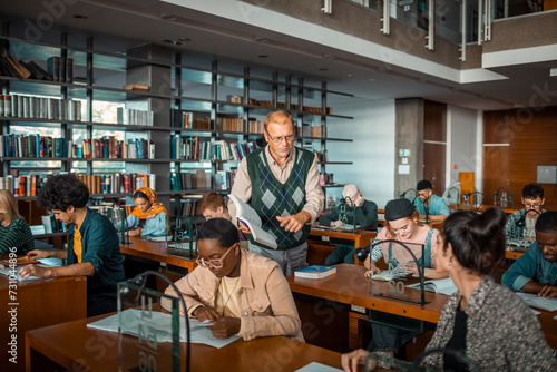 Male professor helping diverse students in college library photo