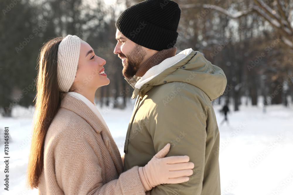 Fototapeta premium Beautiful happy couple in snowy park on winter day