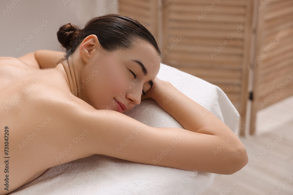 Beautiful woman relaxing on massage couch in spa salon, space for text Beautiful woman relaxing on massage couch in spa salon, space for text