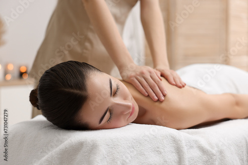 Woman receiving back massage on couch in spa salon