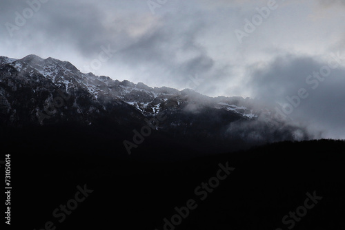 Primo piano di una montagna immersa da nuvole e un po' di neve