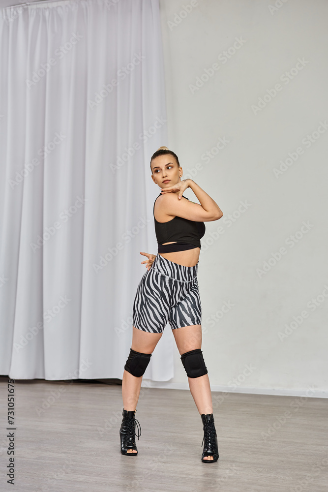 dancer in high heels and zebra-print shorts dances against white wall, showing off her confidence dancer in high heels and zebra-print shorts dances against white wall, showing off her confidence