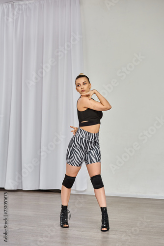 dancer in high heels and zebra-print shorts dances against white wall, showing off her confidence