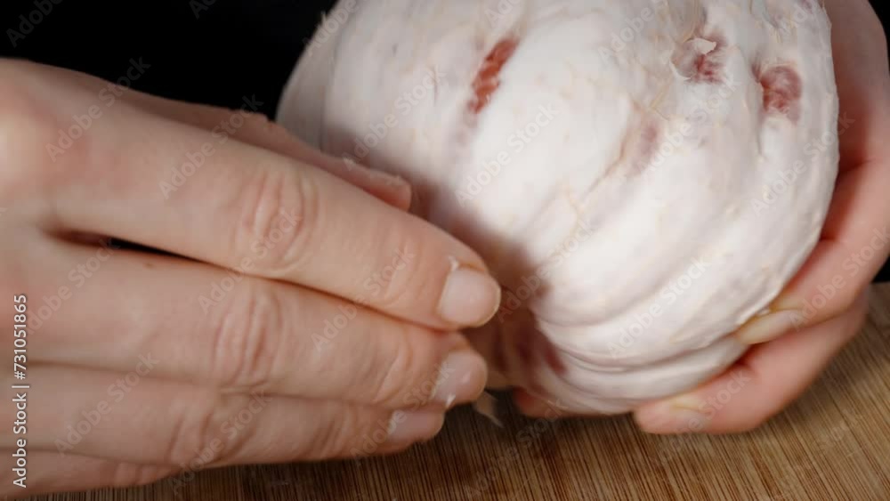 A woman carefully peels the pomelo, removing the tasteless white peel to reach the flesh. A woman carefully peels the pomelo, removing the tasteless white peel to reach the flesh.