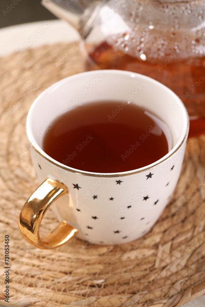 Aromatic tea in cup on wicker mat, closeup Aromatic tea in cup on wicker mat, closeup